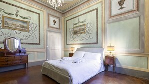 Une chambre spacieuse avec un grand lit, une commode en bois et un miroir.