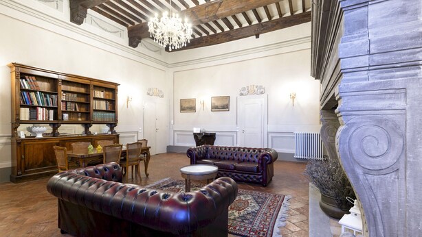 Une pièce spacieuse avec une cheminée, des canapés en cuir, une bibliothèque en bois et un coin repas.