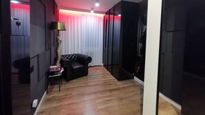 A modern room with a leather sofa, a tall floor lamp, and a wooden floor. - Apartament BDSM Luxxx Częstochowa (Czestochowa)