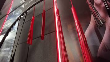 A display of red-handled tools hanging from a ceiling, with a partial view of a person's face in the background.