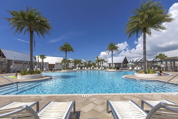 Relax by the central pool surrounded by palm trees and lounge chairs.