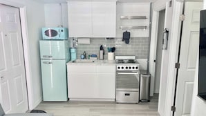 A compact kitchen with white cabinets, a light blue refrigerator, a stove, and a sink. - Newly Renovated Charlotte Harbor - Sunset Inn #7 (Port Charlotte)