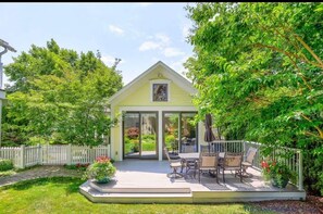 A yellow house with a patio, outdoor furniture, and a white picket fence.