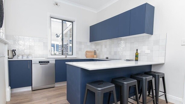 A modern kitchen with a built-in dishwasher, a window, and bar stools. - McNamara Lane - CBD, 7 Smart TVs, Sleeps 11 (Orange)