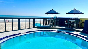 Piscina con indicador de profundidad de 1.2 metros, mobiliario exterior y vista a la playa.
