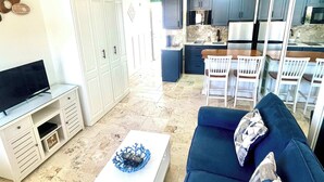Un espacio habitable pequeño con un sofá, una mesa de centro, un televisor y una kitchenette.