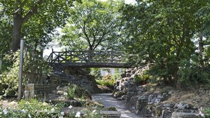 A stone bridge over a narrow path surrounded by lush greenery and white flowers. - 3 bedroom accommodation in St Annes (St Annes)