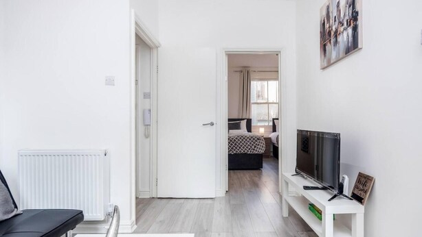 Habitación de hotel moderna con diseño minimalista, que incluye una cama, un televisor, un escritorio y un radiador.