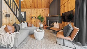 Ein gemütliches Wohnzimmer mit Holzboden, Kamin, Sofa, Sessel und Couchtisch.