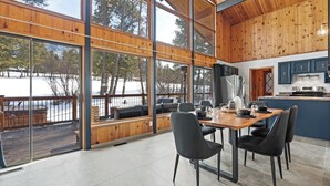 Eine moderne Küche mit großen Fenstern, einem Essbereich mit Stühlen und Blick auf eine verschneite Landschaft.