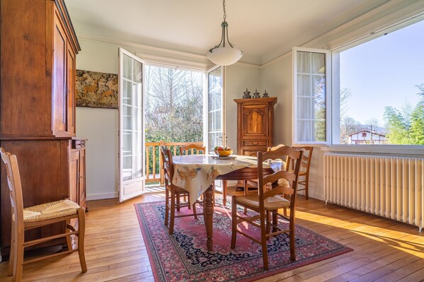 Enjoy meals in this dining area with a round table for four, surrounded by comfortable chairs and a large window offering a view of the surrounding greenery.