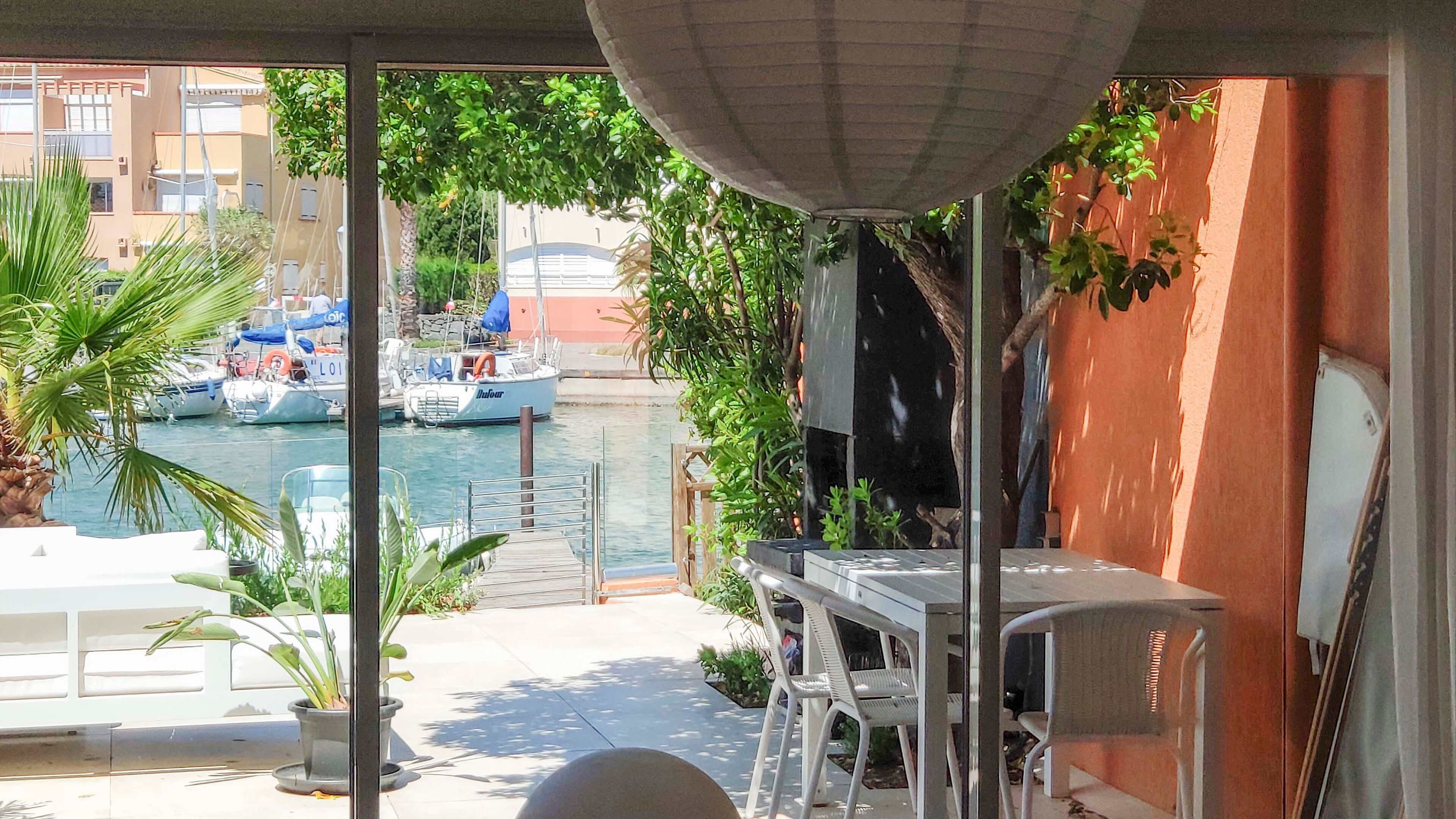 Ein Balkon mit Blick auf Boote auf dem Wasser, inklusive Tisch, Stühlen und Blumentöpfen.