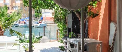 Ein Balkon mit Blick auf Boote auf dem Wasser, inklusive Tisch, Stühlen und Blumentöpfen.