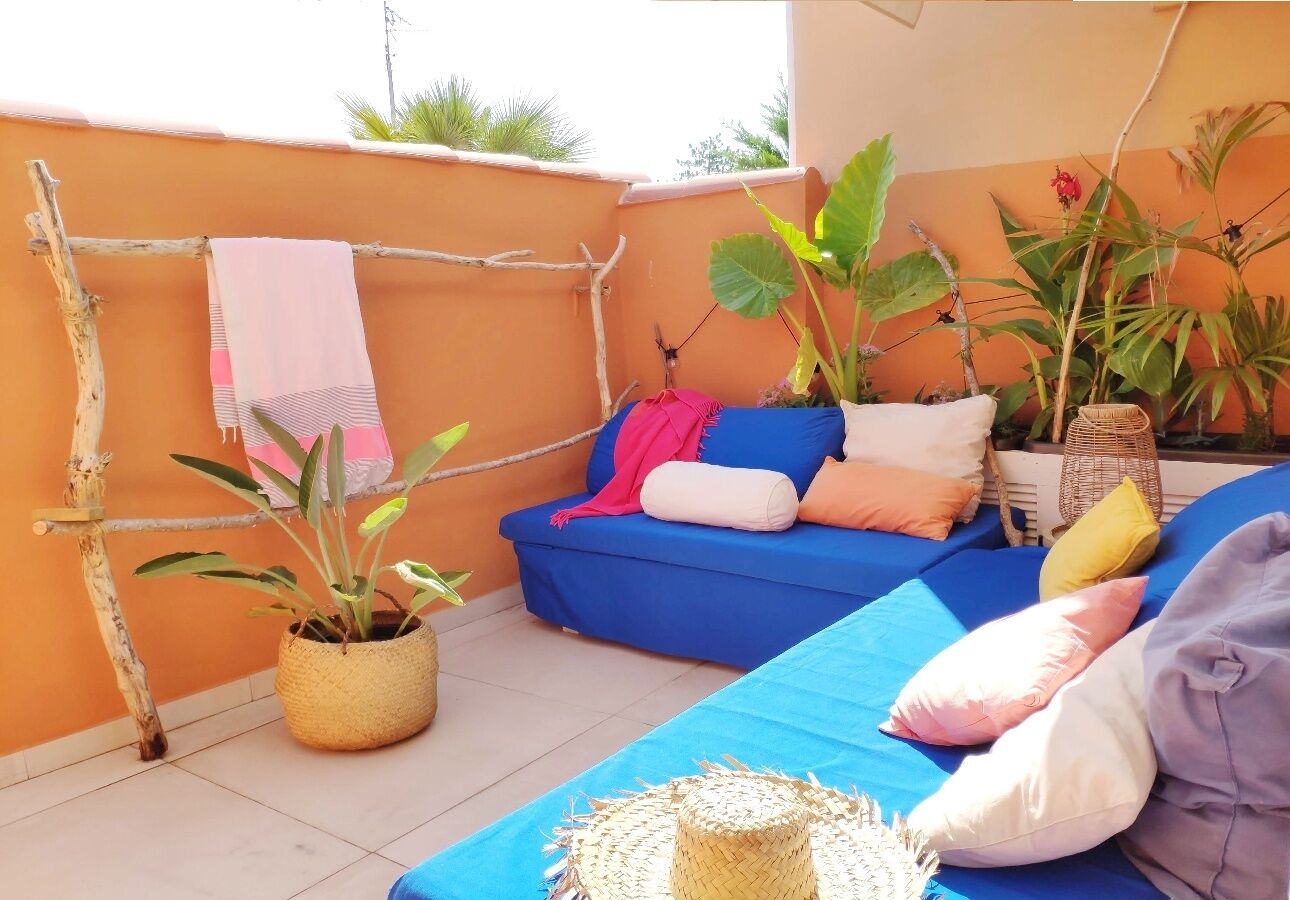 Un balcon avec un canapé bleu, des plantes en pot et un étendoir.