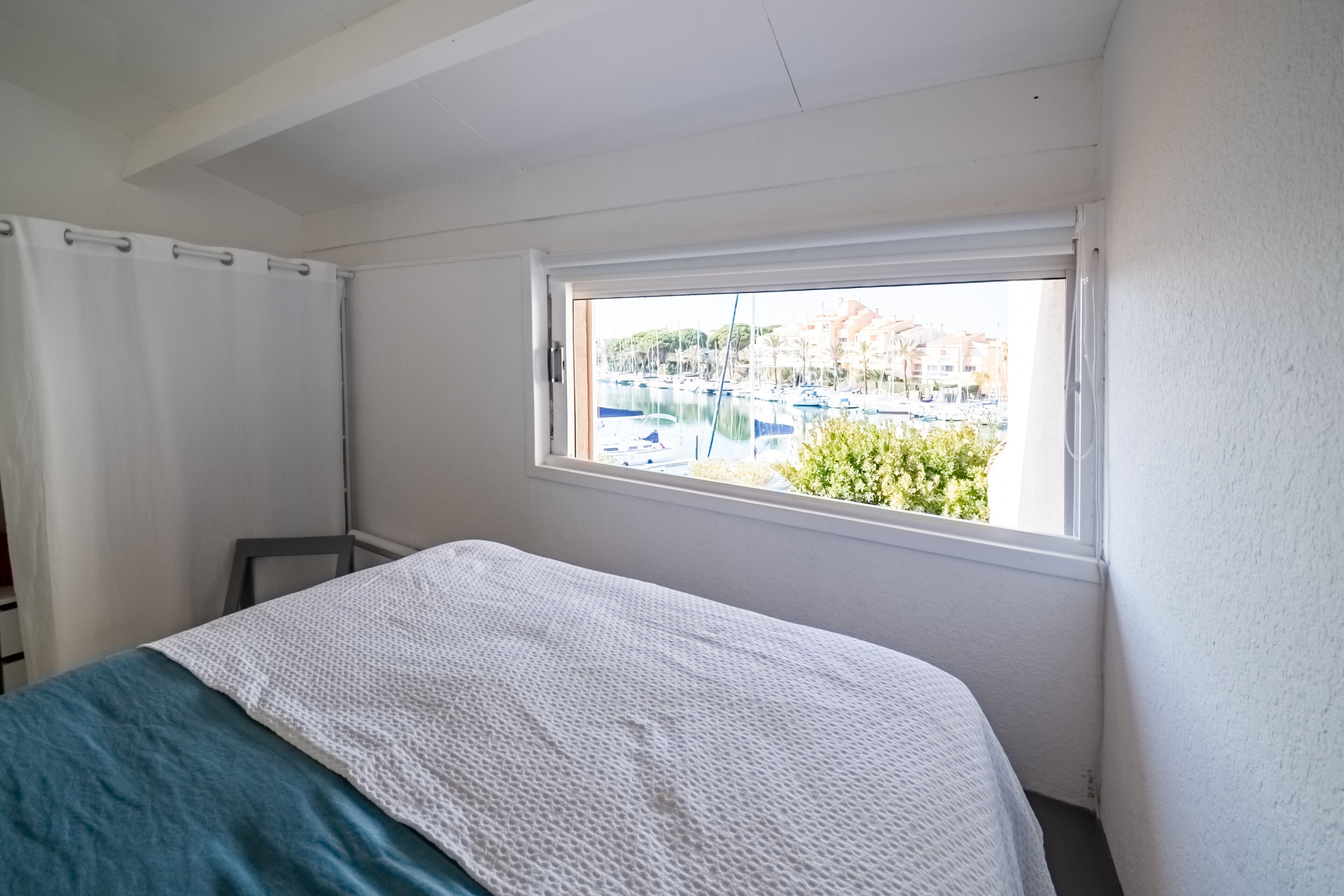 A bedroom with a bed, a window, and a view of a marina.