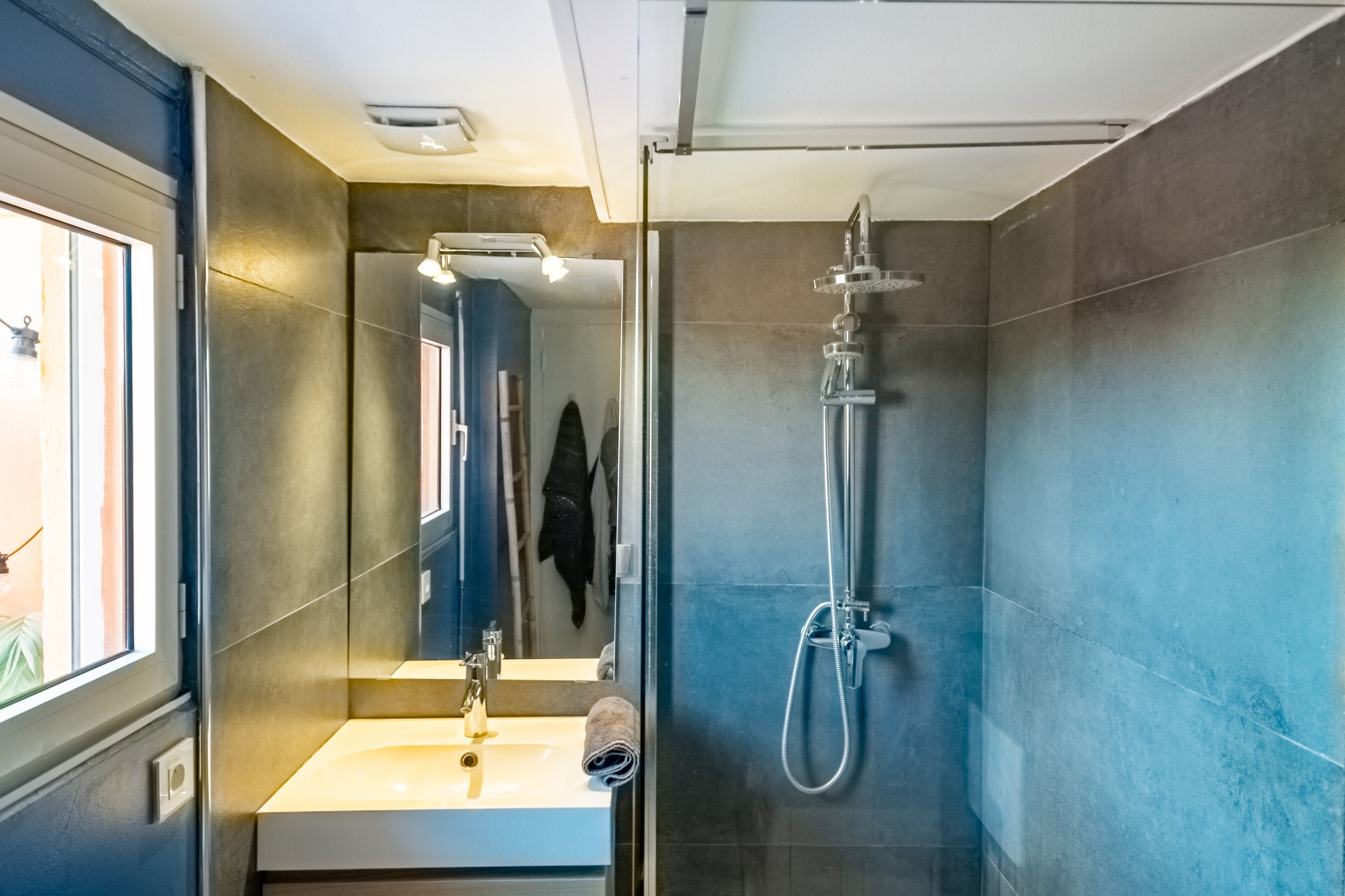 A modern bathroom with a glass-enclosed shower, a sink with a mirror, and a towel on the counter.