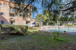 En bostadsbyggnad med en swimmingpool, omgiven av grönska och träd.
