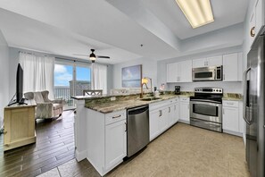 A modern kitchen with white cabinets, stainless steel appliances, and a large island.