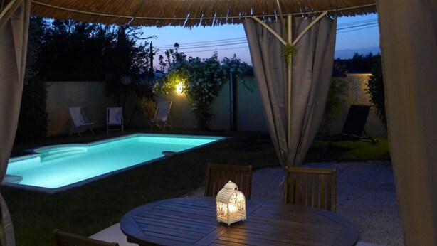 Une terrasse extérieure avec une piscine, une table ronde et des chaises.