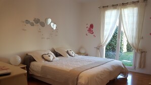 Une chambre à coucher avec un grand lit, des tables de chevet, une fenêtre avec des rideaux et des éléments décoratifs sur les murs.
