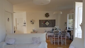 Un salon confortable avec un ensemble de canapés, une table à manger avec des chaises et un petit coin cuisine.