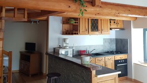 A modern kitchen with wooden beams, a black clock, and a hanging plant. - Converted barn in a small village 5 minutes from langeac (Langeac)