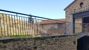 A stone bridge with a metal railing, a stone building with a tiled roof, and a paved path. - Converted barn in a small village 5 minutes from langeac (Langeac)