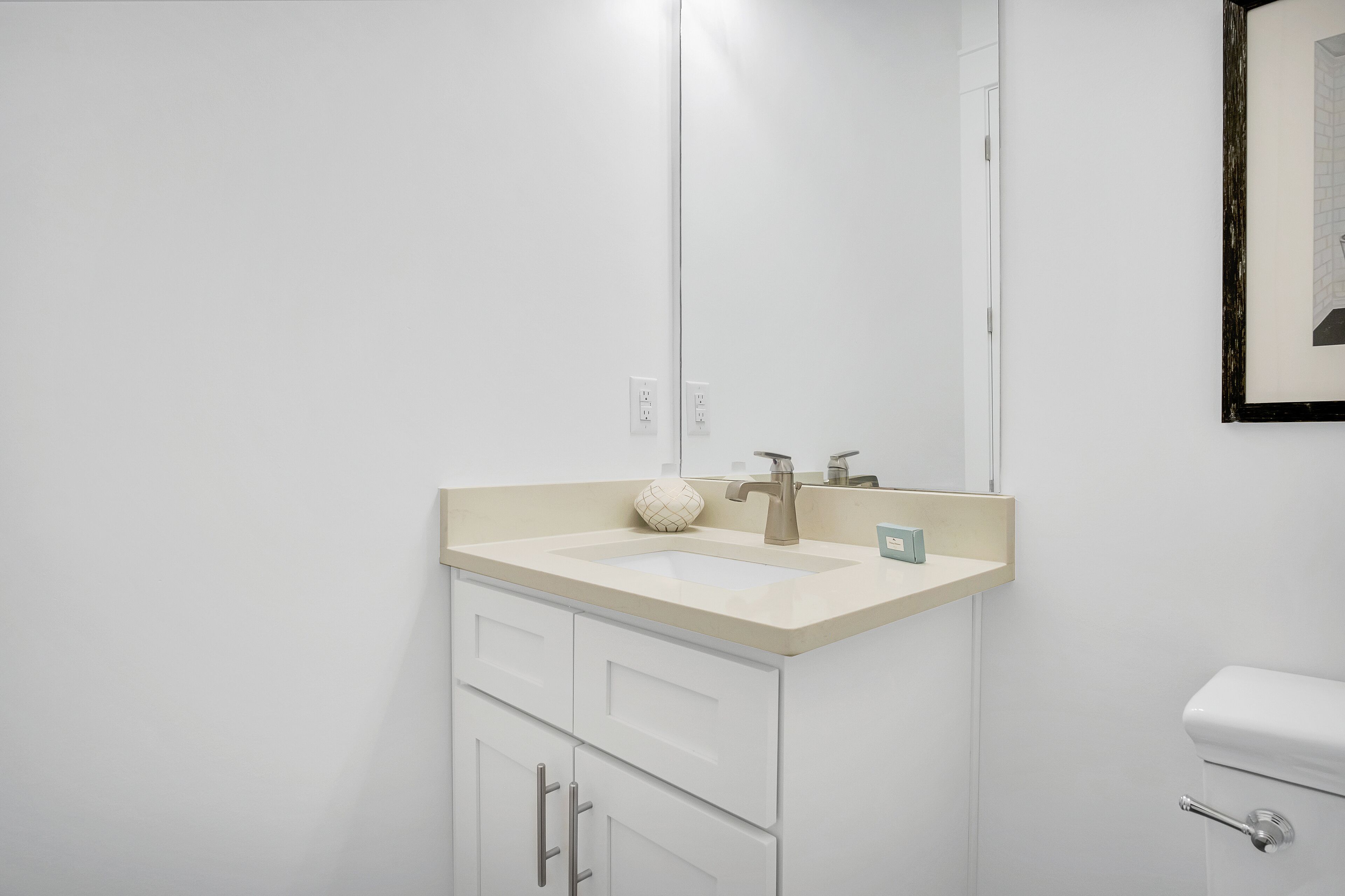 A bathroom with a white sink, a mirror, and a toilet.