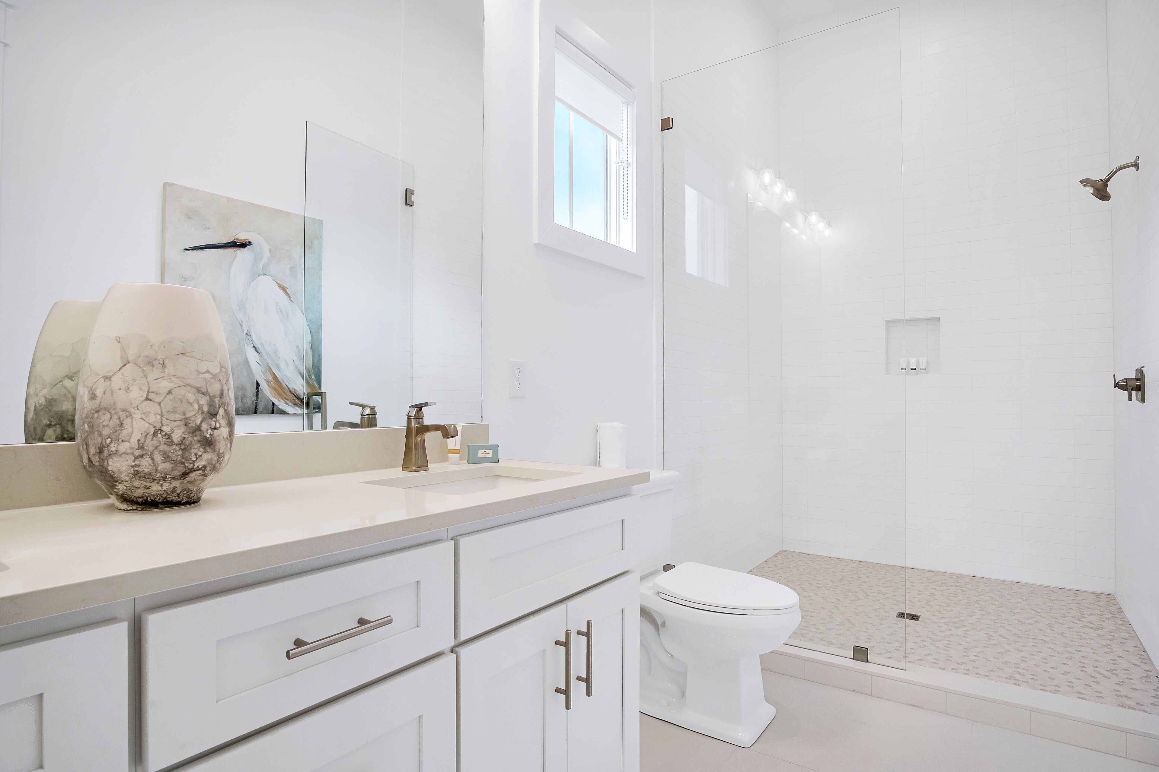 A modern bathroom with a large mirror, a marble vase, a toilet, and a glass-enclosed shower area.