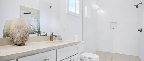 A modern bathroom with a large mirror, a marble vase, a toilet, and a glass-enclosed shower area.