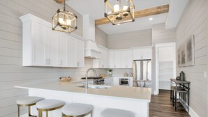 A modern kitchen with white cabinetry, a central island with stools, and pendant lighting. - Aces High|Private Beach Access|Private Pool|Golf Cart (Santa Rosa Beach)