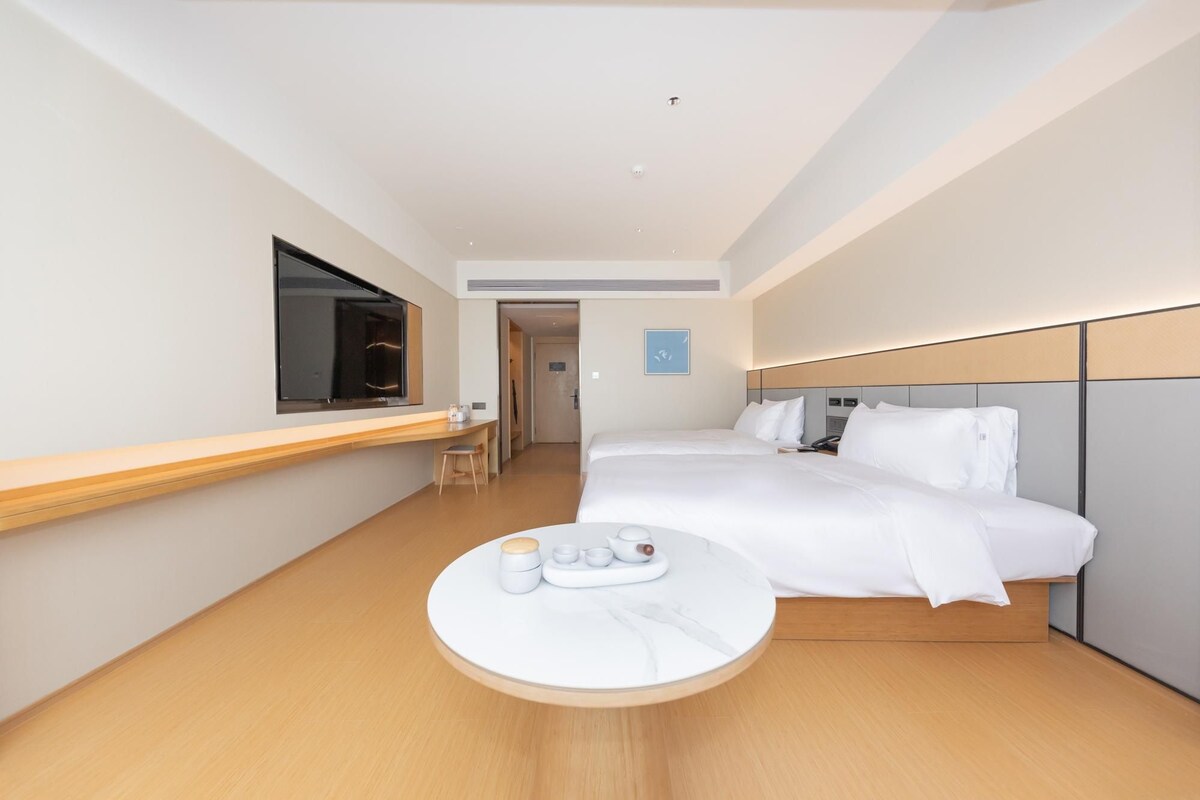 A hotel room with a bed, bedside table, and a small round table with a tea set.