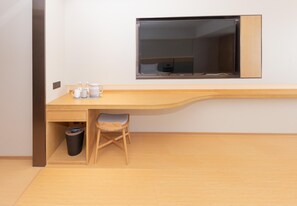 A modern, minimalist room with a wooden desk, a chair, a trash bin, and a television mounted on the wall. - Ji Hotel (Suzhou)