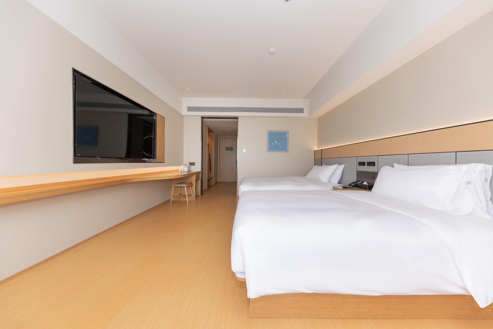A hotel room with a bed, a desk, and a television.
