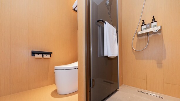 Un baño moderno con inodoro, cabina de ducha y perchero para toallas.