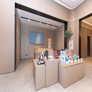 A modern reception area with a flat-screen TV, a reception desk, and a display of various items. - Ji Hotel (Suzhou)