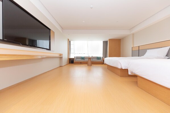 A modern hotel room with a large bed, a TV on the wall, a sofa, and a small table. - Ji Hotel (Suzhou)