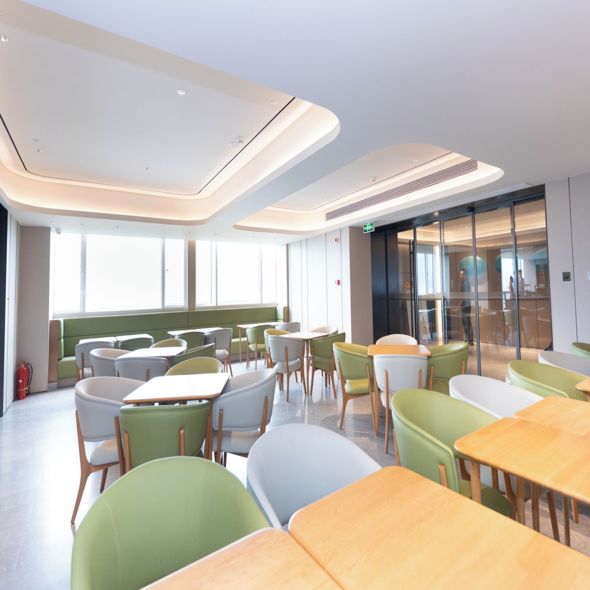 A modern dining area with tables and chairs, large windows, and a clean, contemporary design.