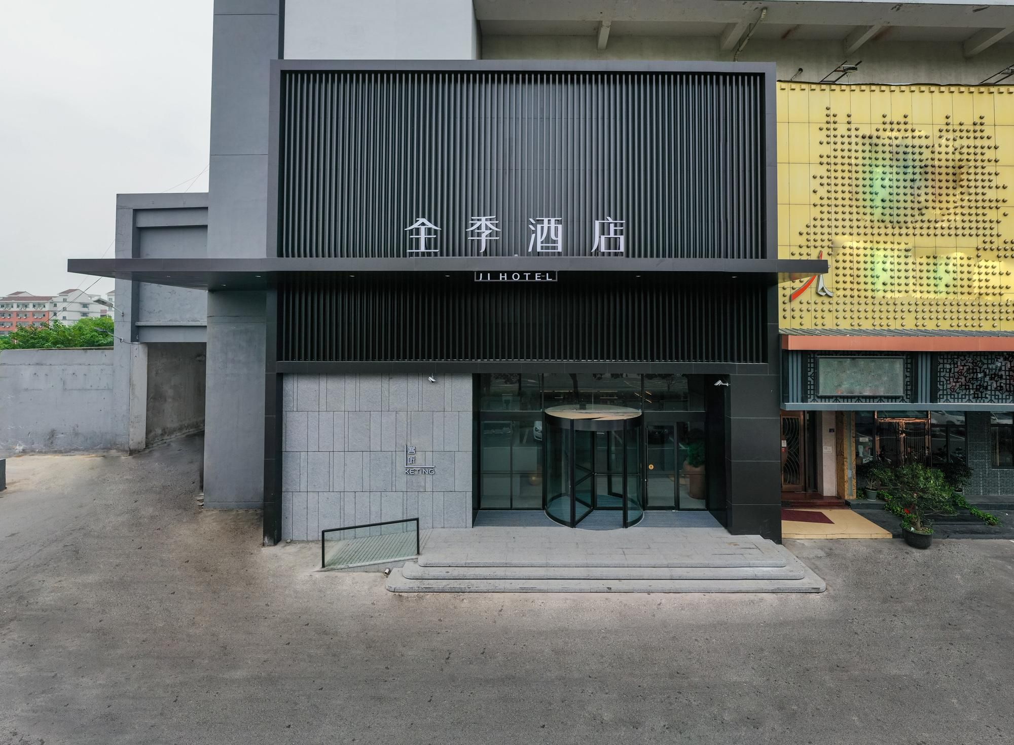 A hotel entrance with a modern design, featuring a vertical panel and a glass door.