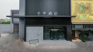 A hotel entrance with a modern design, featuring a vertical panel and a glass door.