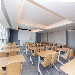 Una sala de conferencias moderna con filas de escritorios y sillas, una pantalla grande y una puerta con cerradura.