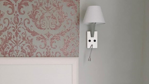 A hotel room with a bed, a nightstand, a wall-mounted lamp, and a patterned wallpaper. - Bed and Best Double room economy (Roma)