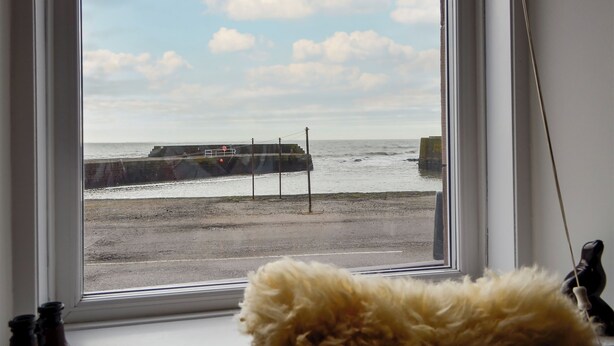 A window with a view of a beach, a pier, and a cloudy sky. - 3 bedroom accommodation in Johnshaven, near Stonehaven (Johnshaven, near Stonehaven)