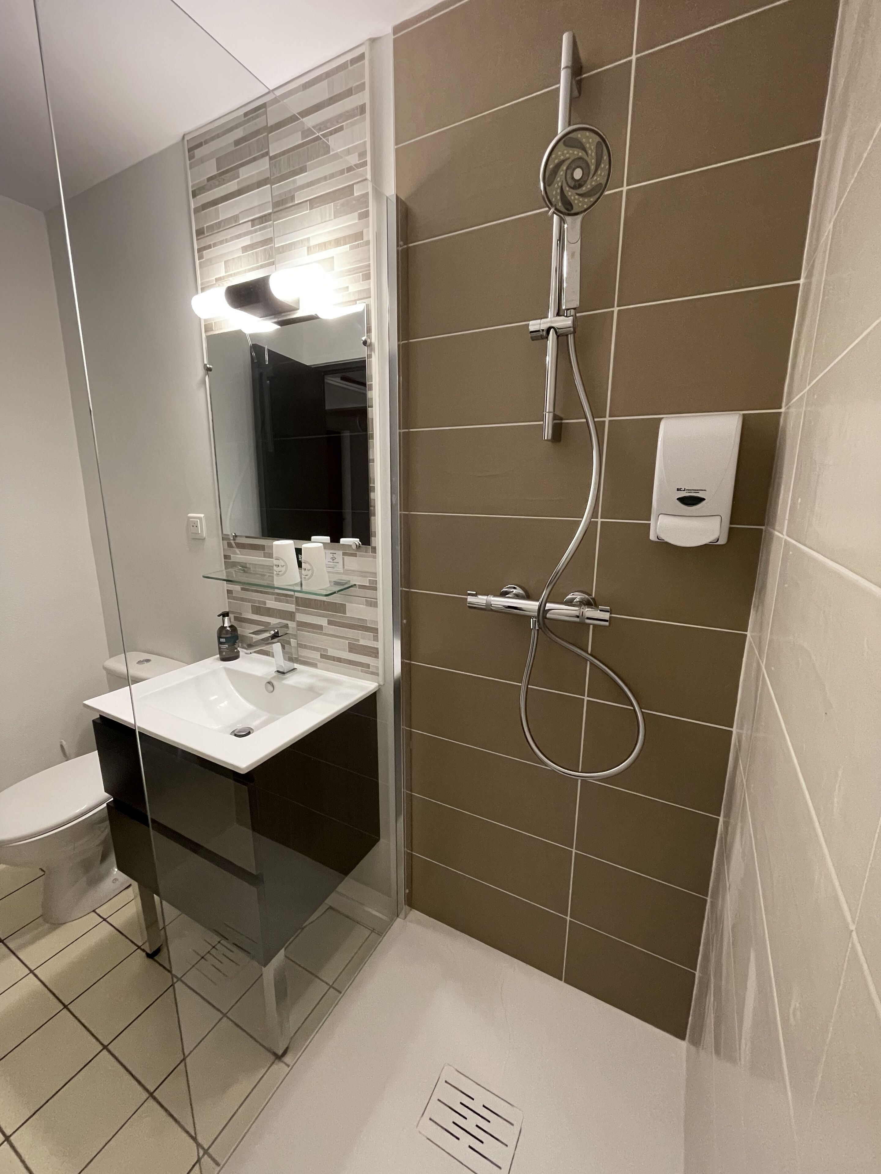 Ein modernes Badezimmer mit Duschkabine aus Glas, einem weißen Waschbecken und einem Spiegel.