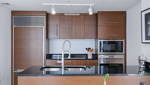 Een moderne keuken met houten kastjes, roestvrijstalen apparatuur en een centraal kookeiland met spoelbak.