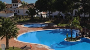 Un complex turístic amb diverses piscines, una vista despejada de l'oceà i una zona de gespa ben cuidada.