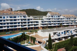 A multi-story hotel with a pool area, including a small pool and a larger pool with a slide.