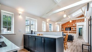Una cocina moderna con armarios oscuros, una encimera blanca y una pared de ladrillo decorativa.