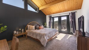 A bedroom with a large bed, a wooden ceiling, a sliding glass door, and a TV. - Mountain Views at Rim Country Chalet  (Payson)