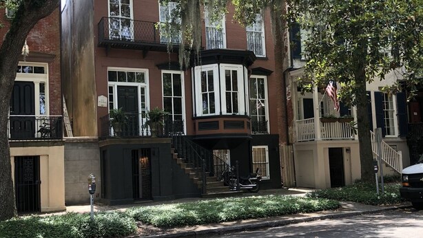 A row of brick townhouses with a central building featuring a bay window and a small porch. - Elegant Savannah Patio Apartment! An Arty Flair on Jones Street (Savannah)